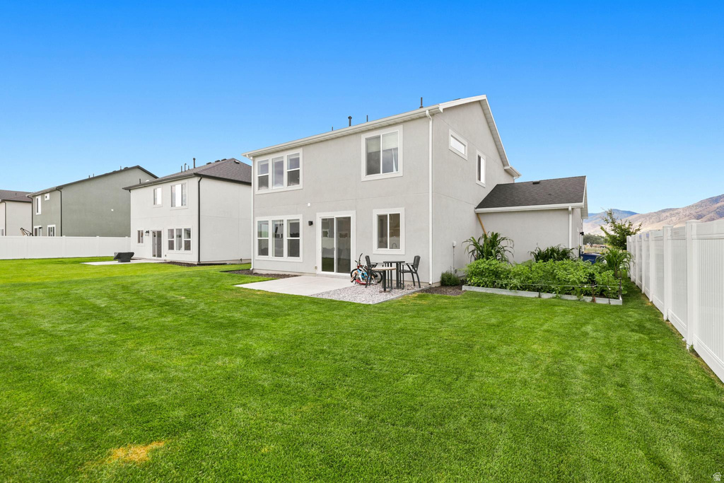 Expansive green lawn with a white vinyl privacy fence, a concrete patio, and a raised garden bed