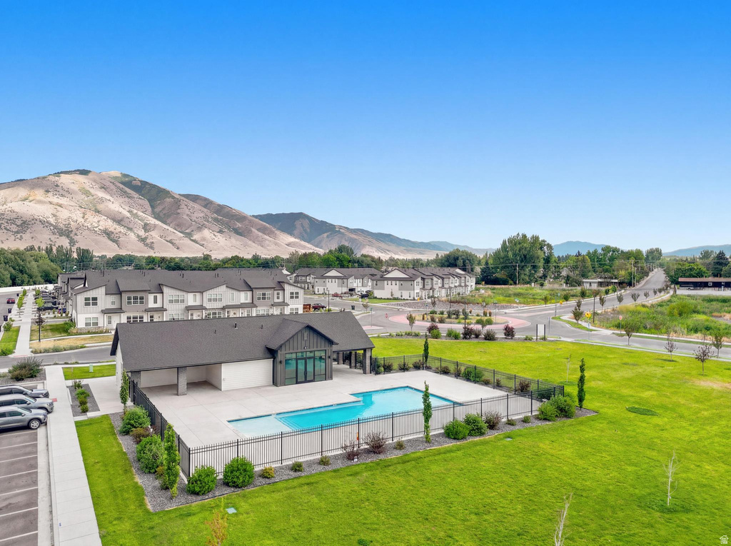 Community amenities featuring a rectangular swimming pool, a modern clubhouse with dark siding and large windows, and a paved parking area