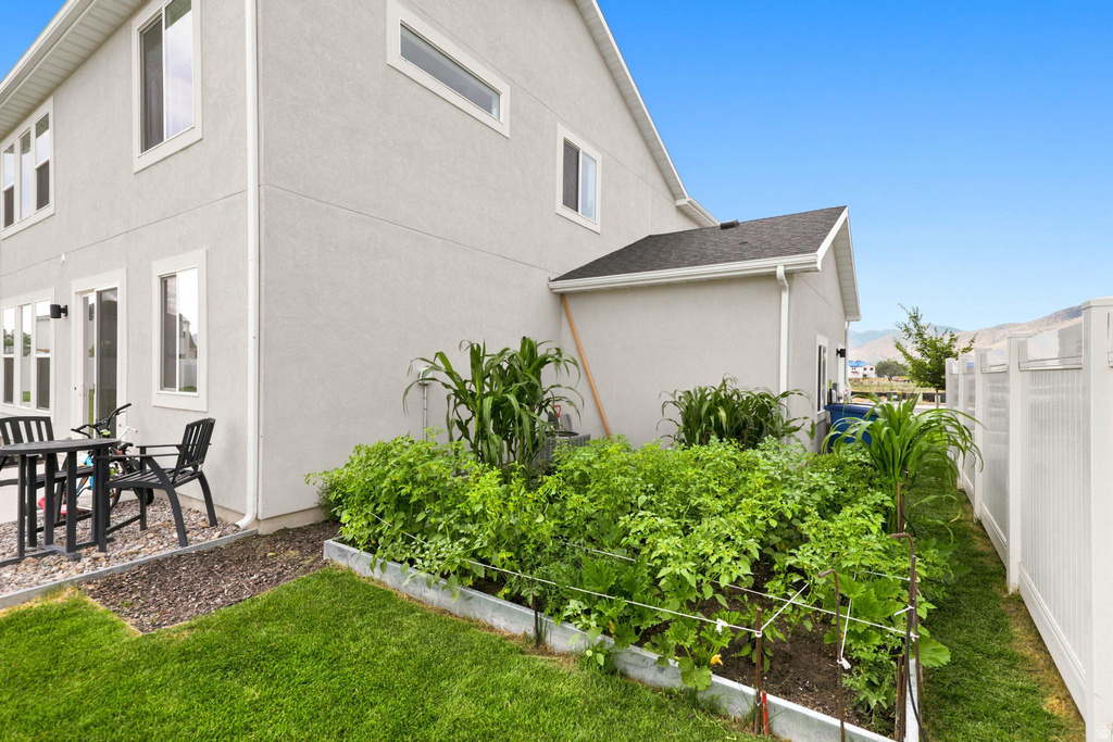 Manicured backyard featuring a lush lawn and a raised garden bed