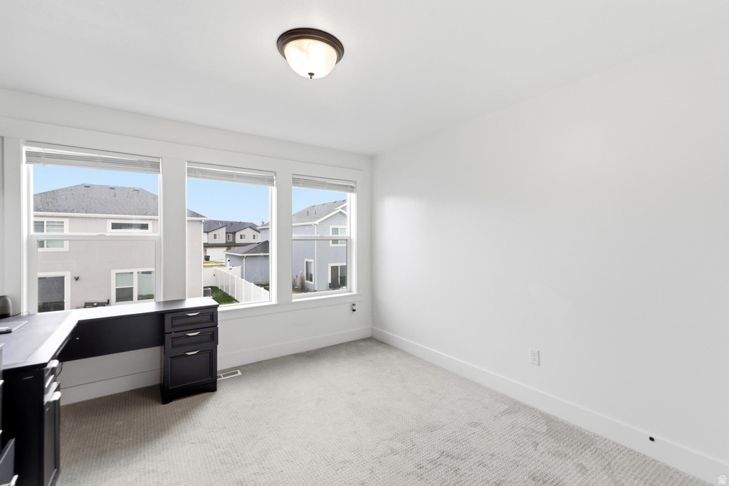 Bright room featuring three large windows, white walls, and light-toned carpeting