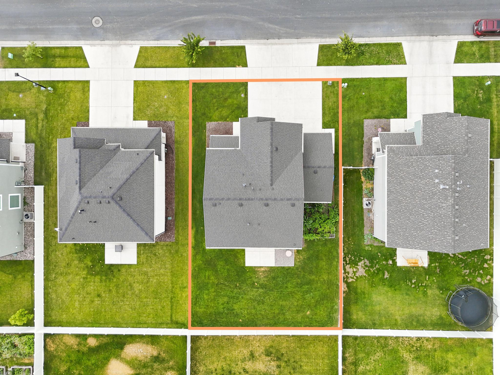 Aerial view of a residential property featuring a large green lawn surrounding a grey-roofed home