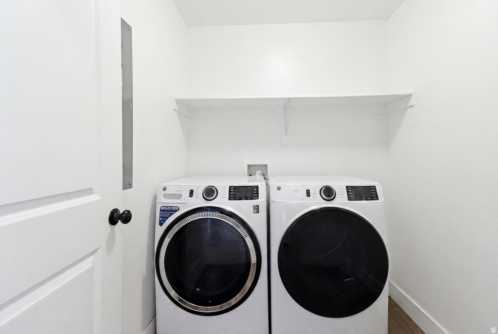 Dedicated laundry area featuring a built-in shelving unit, white walls, and wood-finish flooring