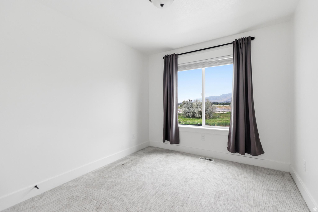 Bright room featuring white walls, gray patterned carpeting, a large window, and white trim