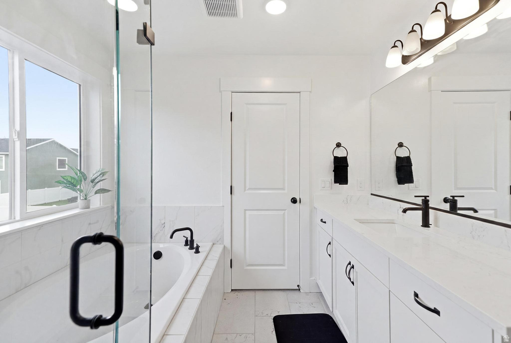 Bathroom featuring a built-in soaking tub, glass-enclosed shower, dual vanity with undermount sinks, and matte black fixtures