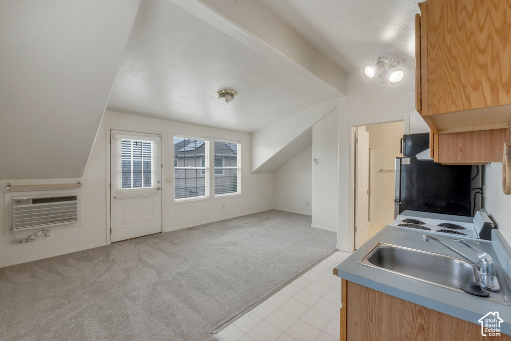 Compact kitchen featuring a four-burner electric range, stainless steel sink, and wood cabinetry