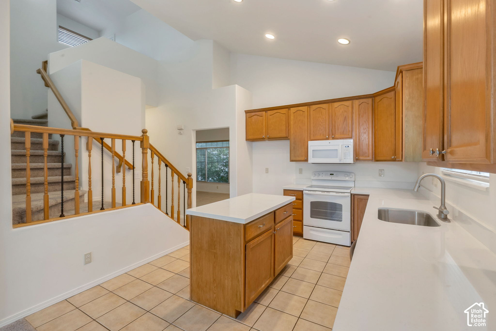 Kitchen with light wood cabinetry, white countertops, tile flooring, and a central island