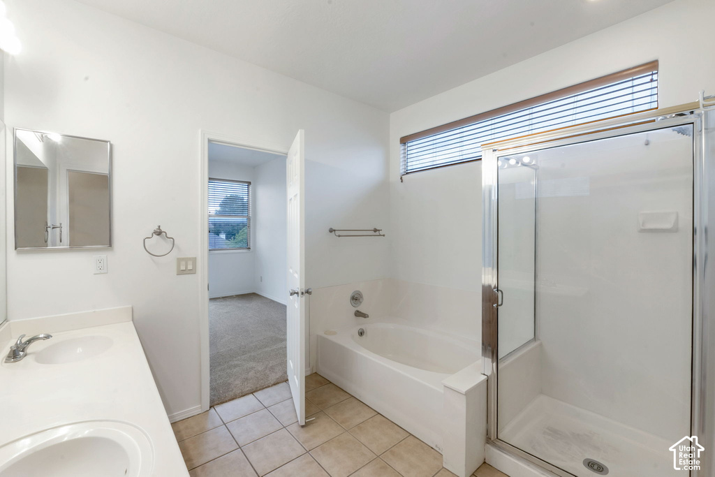 Bathroom featuring a dual vanity with a white countertop, a built-in tub, a separate glass-enclosed shower, and a high horizontal window with blinds