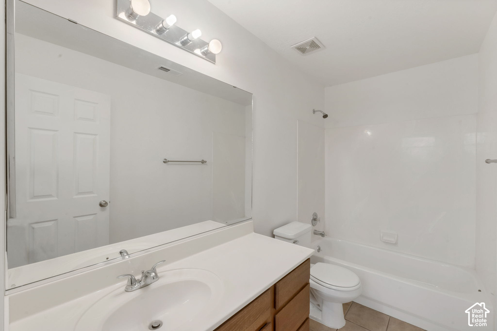Bathroom featuring a vanity with a white countertop and integrated sink, a large wall-mounted mirror, and a built-in bathtub with shower