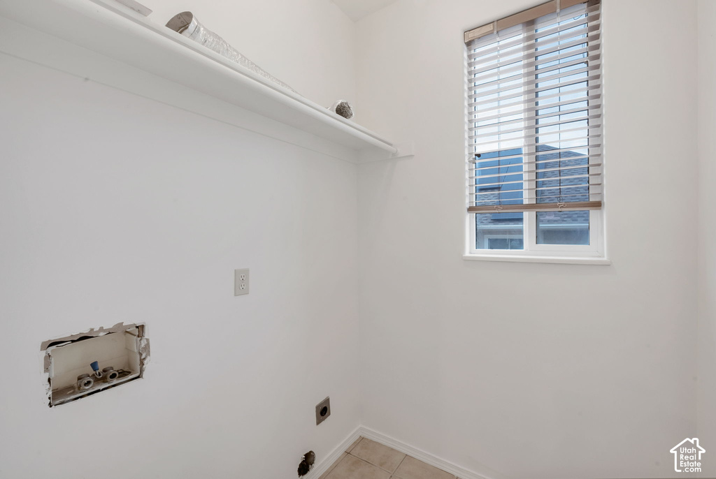 Utility area featuring a single fixed shelf, window with horizontal blinds, and tile flooring