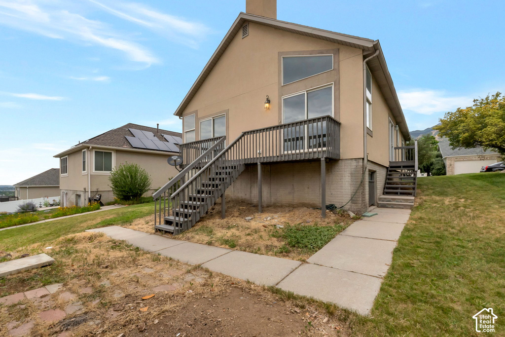 Rear exterior featuring a multi-level deck with wooden railings, large sliding glass doors, and expansive angled windows