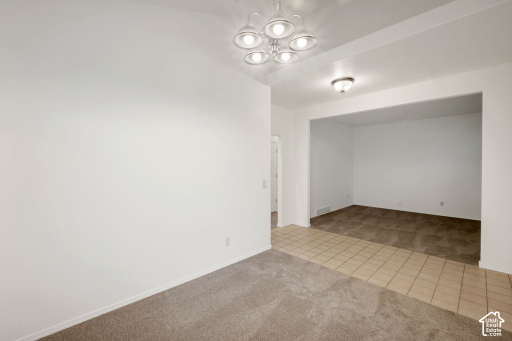 Spacious interior room with neutral-toned carpeting, a contemporary ceiling light fixture, and white wall finishes