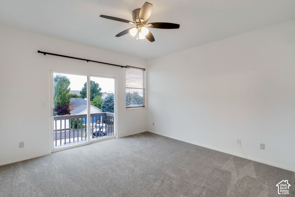 Carpeted room featuring a ceiling fan with integrated lighting, a sliding glass door providing outdoor access, and a window with horizontal blinds