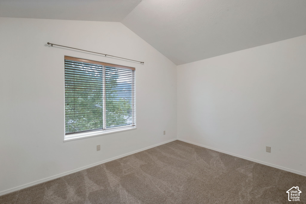 Room featuring a vaulted ceiling and neutral-toned carpeting