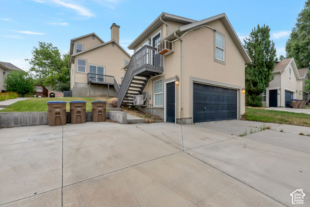 Exterior stucco siding with a prominent black garage door, a private exterior staircase leading to an upper-level balcony, and an additional exterior access door