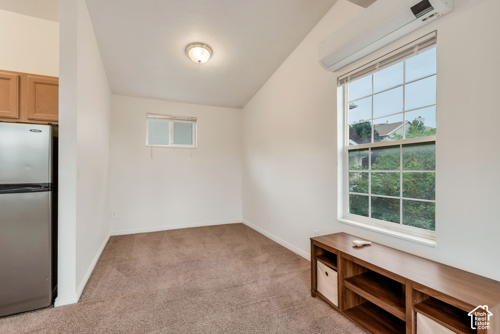 Vaulted ceiling room featuring a large grid-pattern window, recessed lighting, and a wall-mounted air conditioning unit
