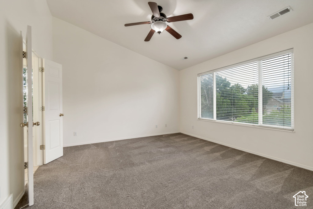 Spacious room featuring vaulted ceilings, a ceiling fan with integrated lighting, and neutral-toned carpeting