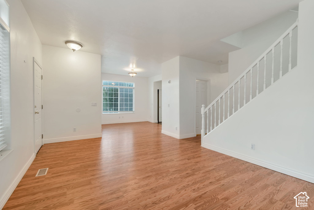 Spacious interior featuring wood-finish flooring, white walls, and a prominent staircase with white balusters
