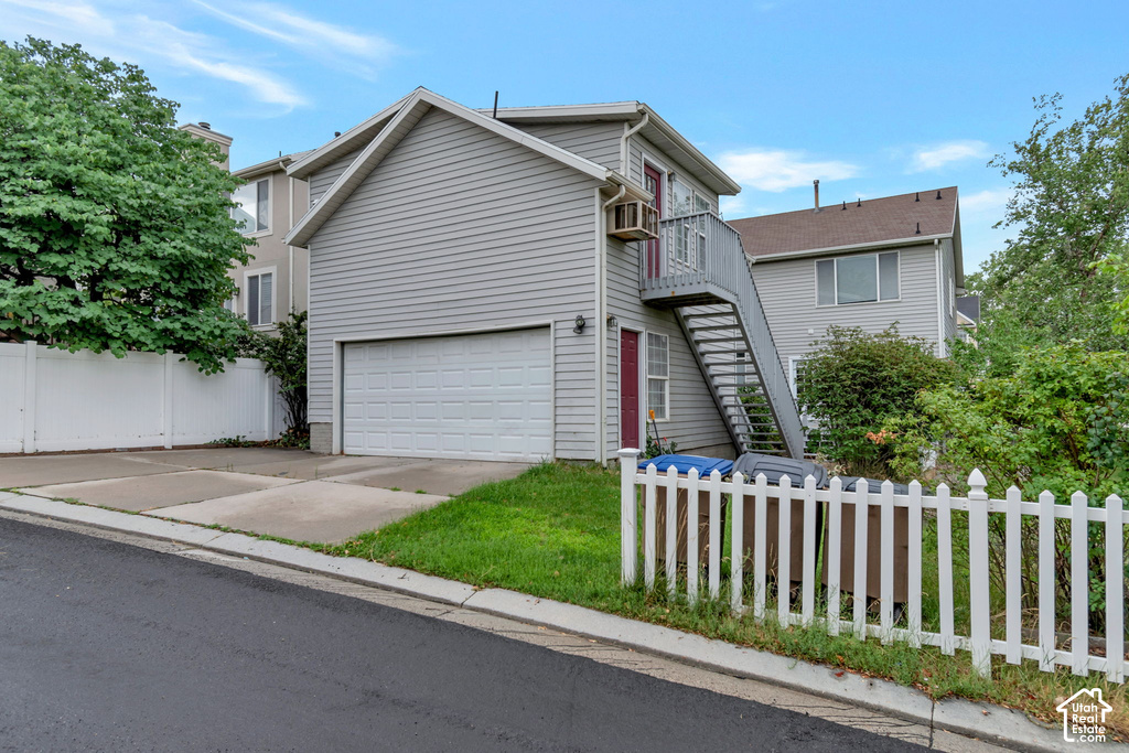 Two-story residence featuring light gray siding and an attached garage with a white sectional door
