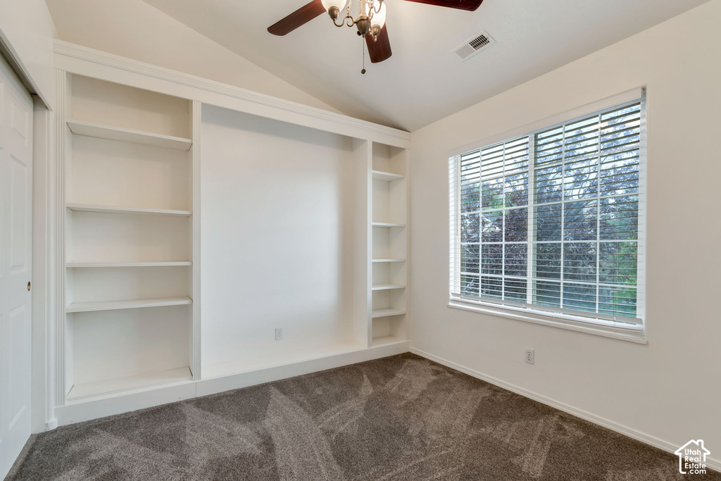 Room featuring built-in white shelving, vaulted ceiling, and a ceiling fan with integrated lighting