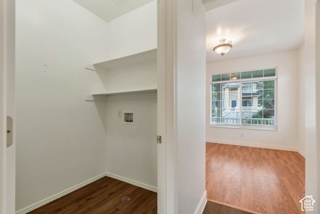 Utility area with wood-finish flooring and built-in shelving, complemented by an adjacent room featuring a large window, recessed lighting, and a semi-flush mount ceiling fixture