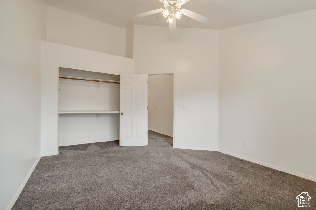 Spacious interior room with neutral-toned walls, vaulted ceiling, and grey carpet