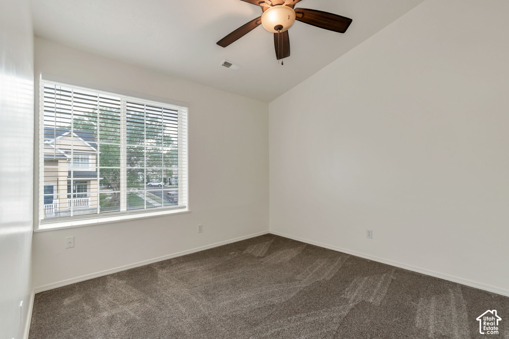 Carpeted room featuring a large window with white blinds, a ceiling fan with integrated lighting, and white baseboards