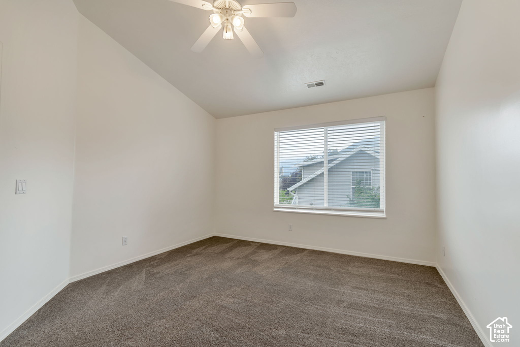 Spacious room featuring vaulted ceilings, neutral-toned carpeting, a ceiling fan with integrated lighting, and a large window with white blinds