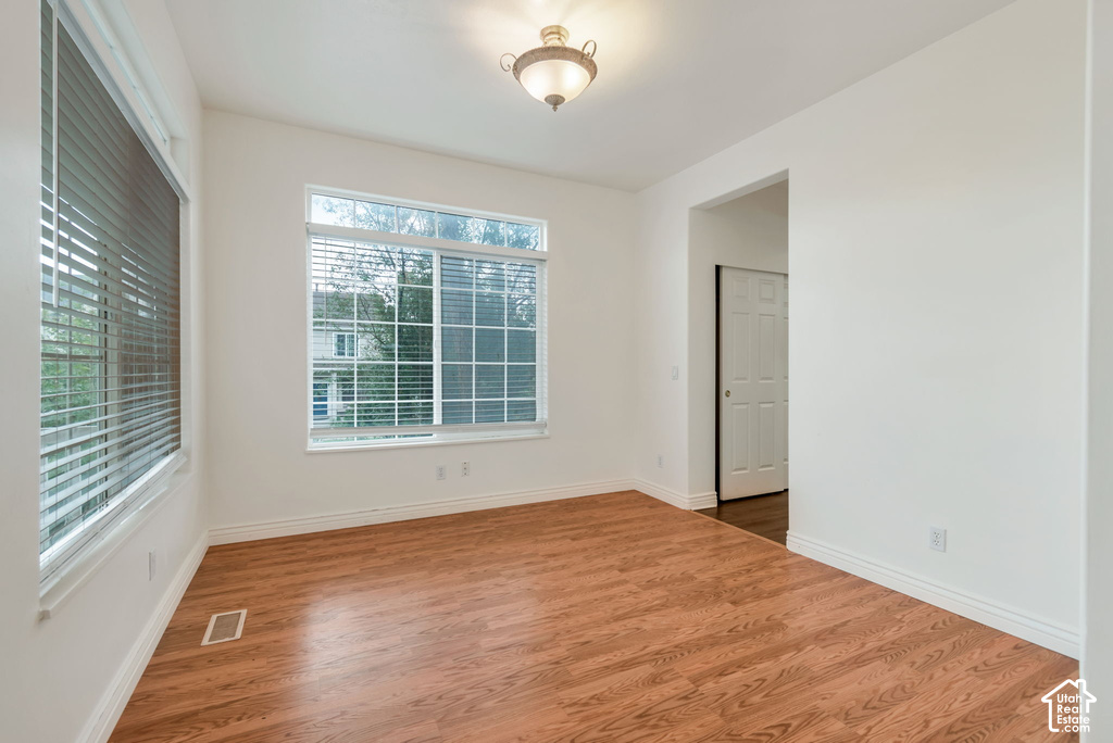 Spacious room featuring wood-finish flooring, white baseboards, and bright white walls