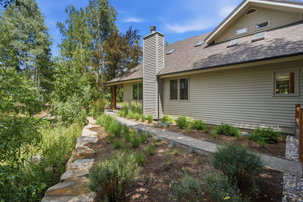 Exterior siding with multiple windows and a shingled roof, featuring a chimney with horizontal siding