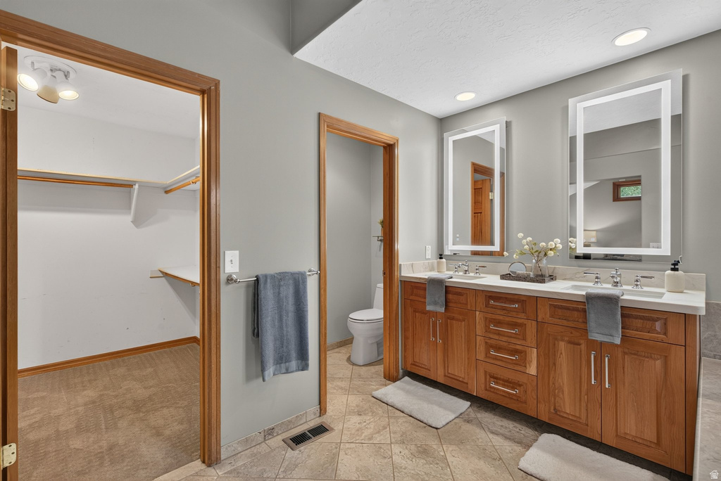 Bathroom featuring a dual vanity with wood cabinetry, light countertops, and two illuminated rectangular mirrors