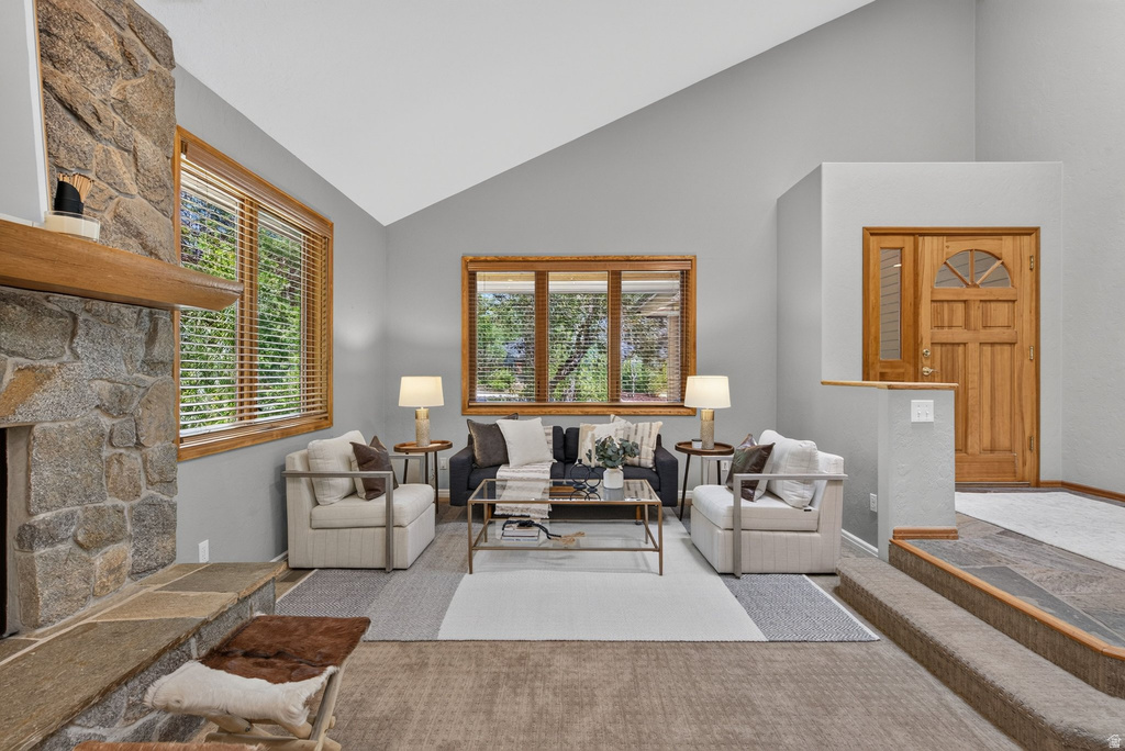 Spacious living area featuring a vaulted ceiling and a stone fireplace