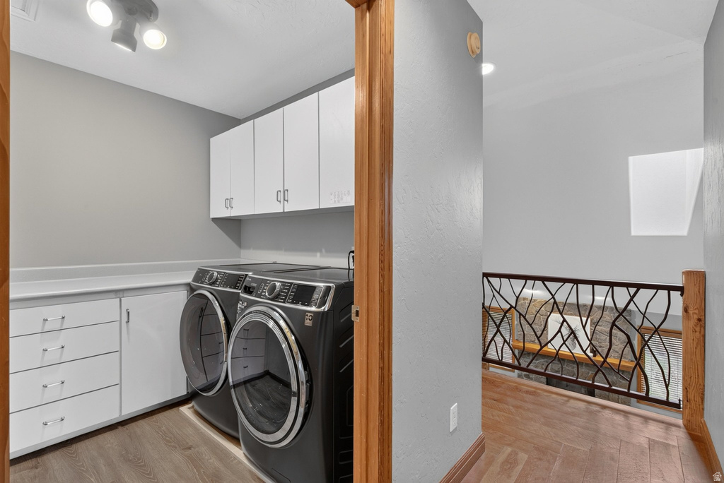 Dedicated laundry area featuring white cabinetry, integrated countertop space, and wood-finish flooring