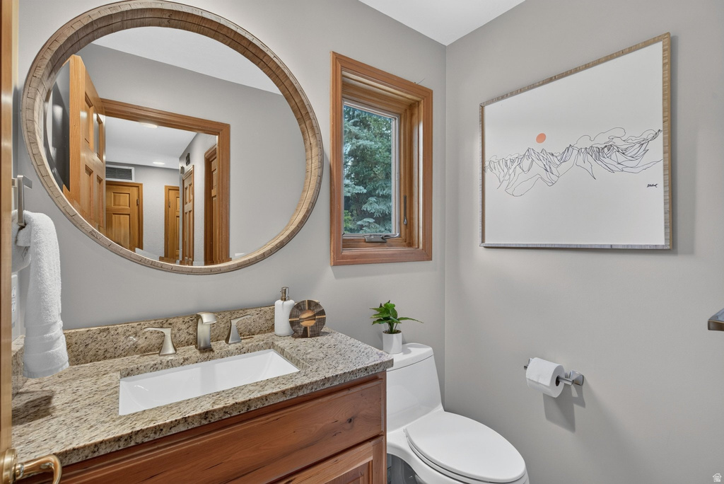 Bathroom featuring a wood-finish vanity with a light-toned granite countertop and an undermount sink