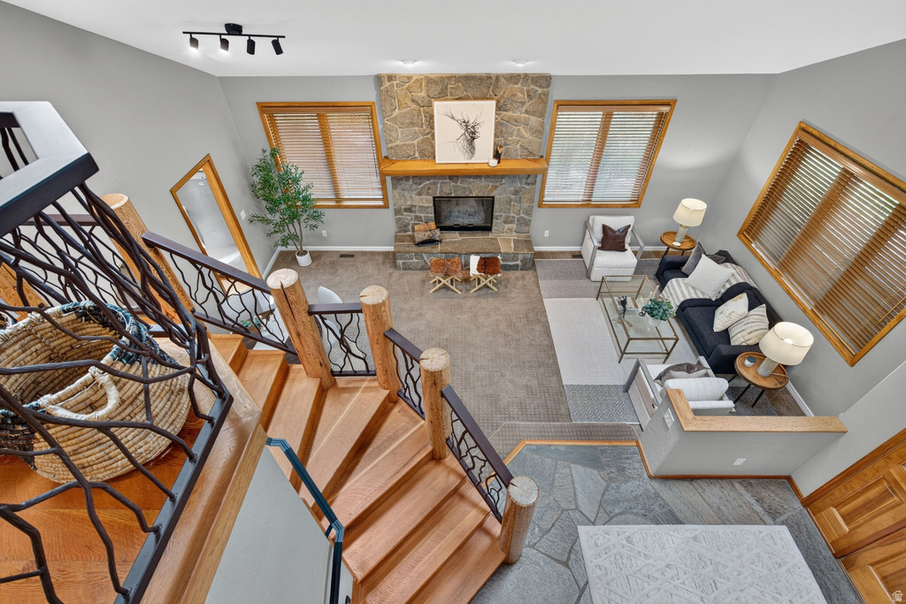Multi-level living space featuring a stone fireplace with a wood mantel, wood-finish flooring, and natural light from multiple windows
