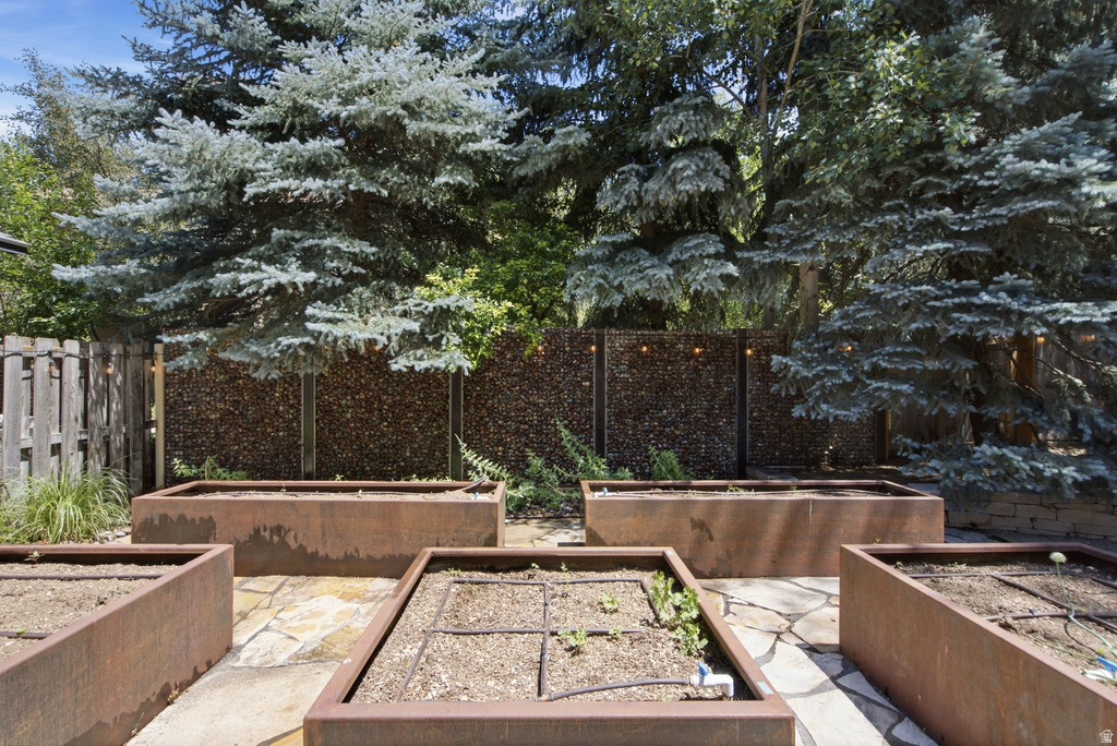 Landscaped garden area featuring multiple rectangular raised planters, flagstone patio, and a decorative privacy fence with integrated lighting