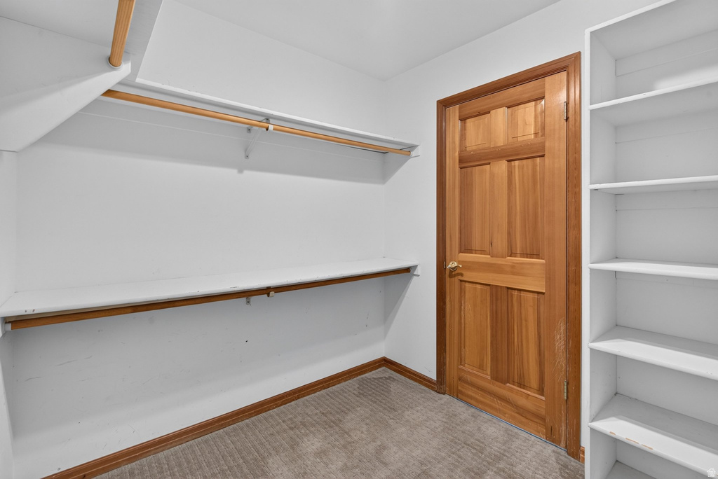 Walk-in closet featuring built-in shelving, two clothing rods, a lower shelf, wood-finish baseboards, and a paneled wood-finish door with a brass-tone knob