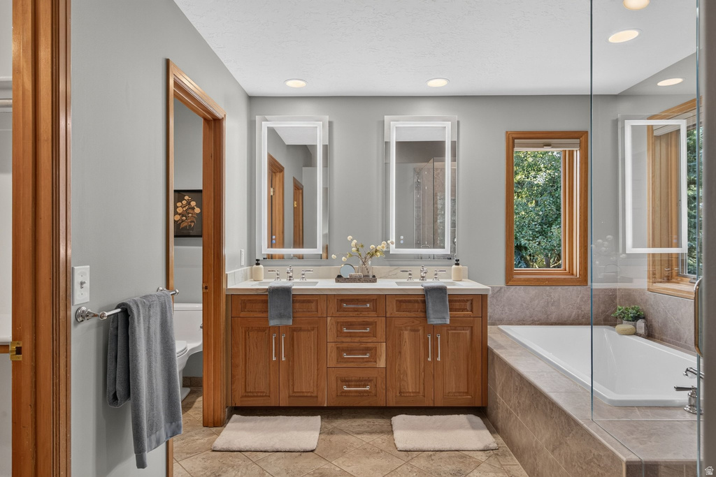 Bathroom featuring a double vanity with wood cabinetry, light-toned countertop, and dual illuminated rectangular mirrors