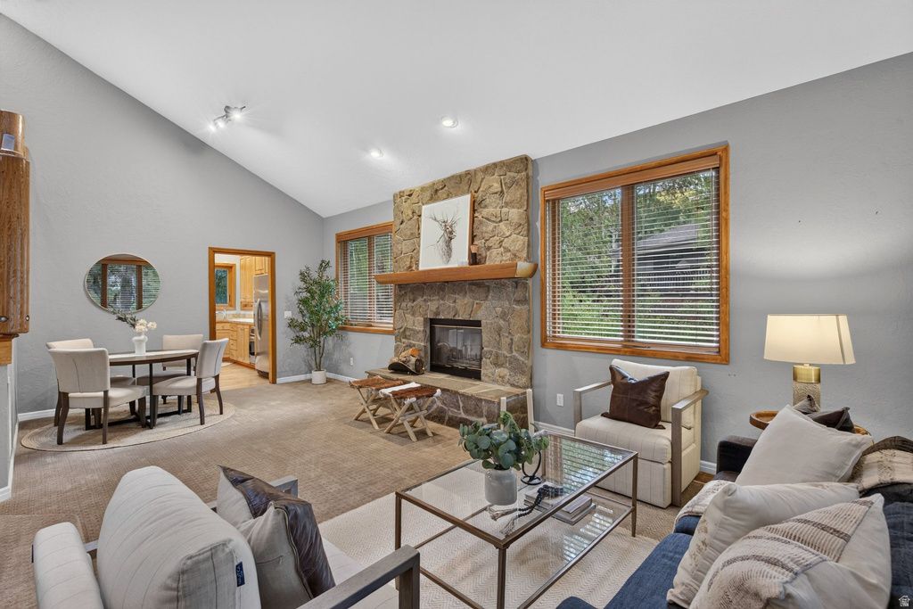 Vaulted ceilings elevate this living space featuring a stone-clad fireplace with a wood mantle