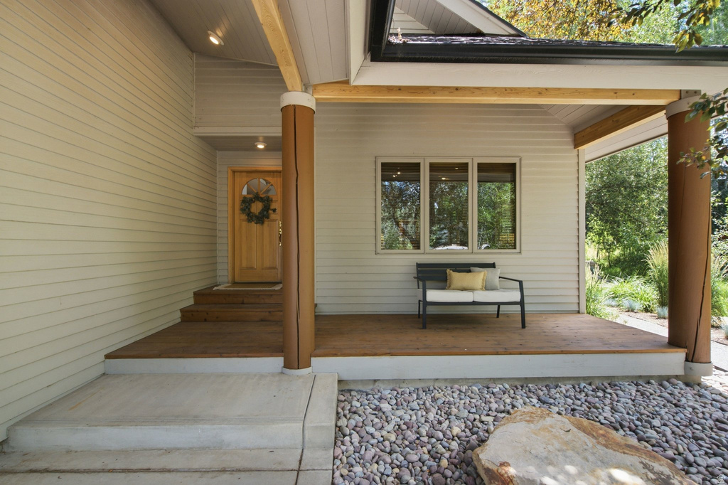 Inviting covered front porch with a natural wood door, coordinating wood-finish decking, and recessed lighting