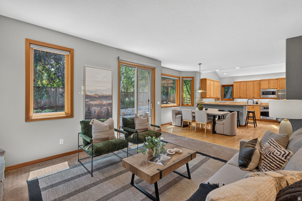 Open-concept living space featuring wood-finish flooring, a slider to the exterior, and large windows with wood trim