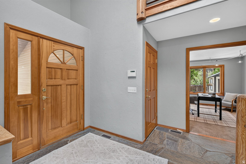 Entryway featuring a natural wood front door with an arched transom window and a sidelight