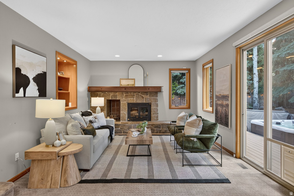 Living area featuring a stone fireplace with a wood mantle, a built-in illuminated wood shelving unit, and warm gray wall finishes