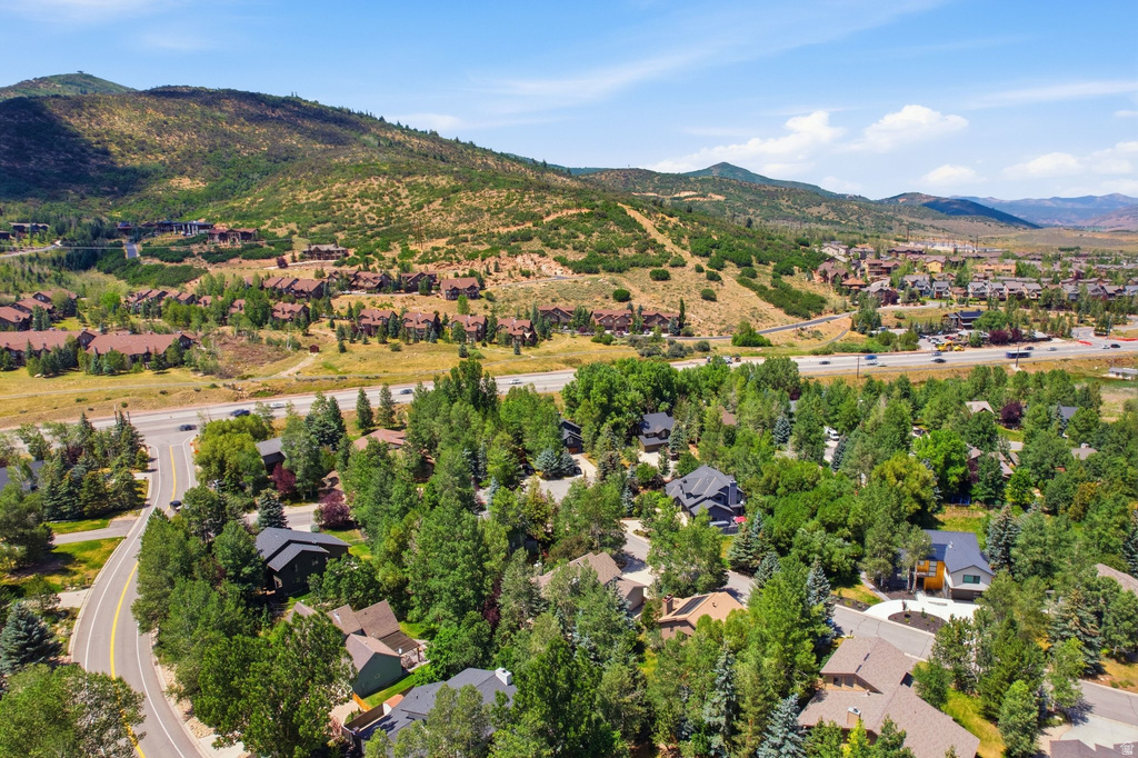 Aerial perspective showcasing a residential area with varied home styles, mature trees, and mountainous terrain