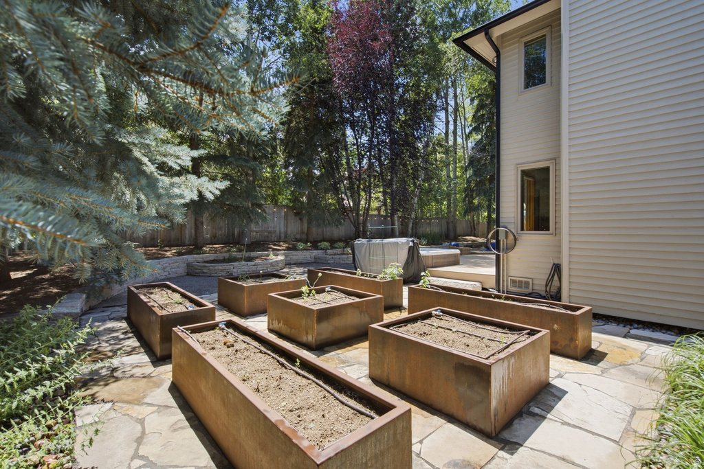 Expansive flagstone patio area featuring multiple rectangular raised garden beds
