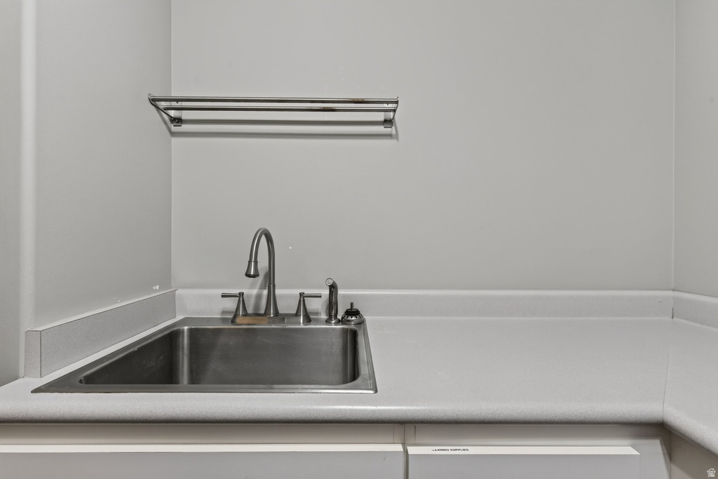 Stainless steel utility sink with a high-arc faucet, integrated into a white countertop