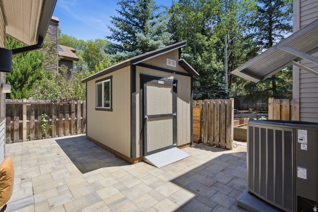 Paver patio featuring a shed with a single window and ramped entry