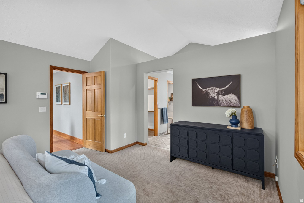 Vaulted ceiling room with light gray walls and plush carpeting