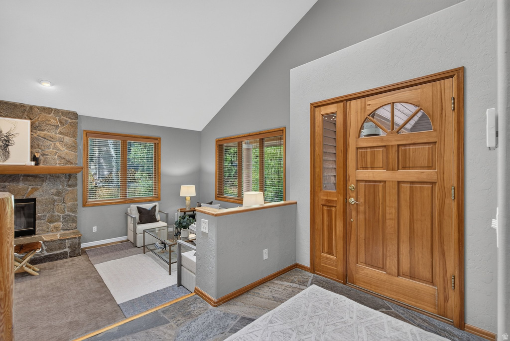 Entryway featuring a solid wood door with an arched transom window and sidelight, slate tile flooring, and a vaulted ceiling
