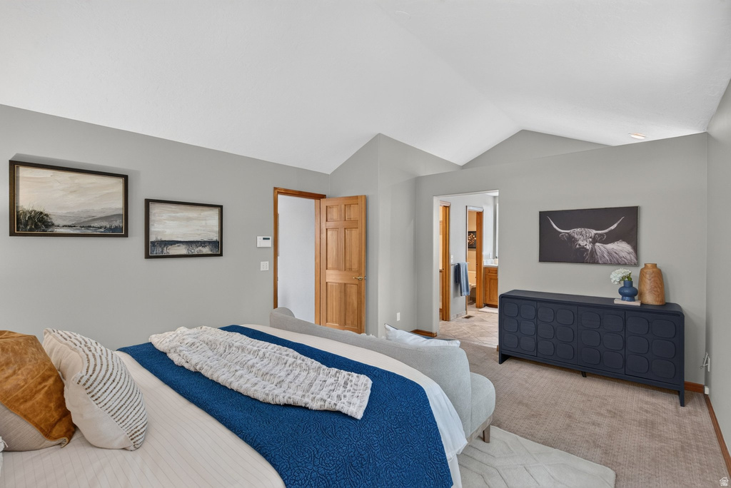 Vaulted ceiling bedroom featuring neutral wall tones, wood-paneled door, and carpeted flooring