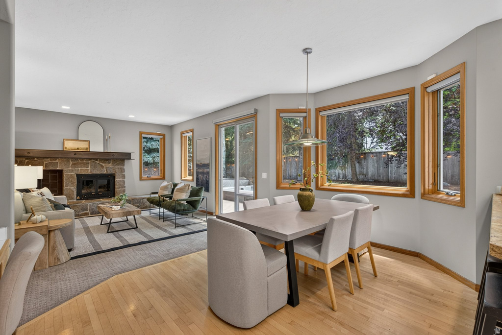 Open-concept living and dining areas featuring wood-finish flooring, a stone-clad fireplace with a wood mantle, and a sliding glass patio door